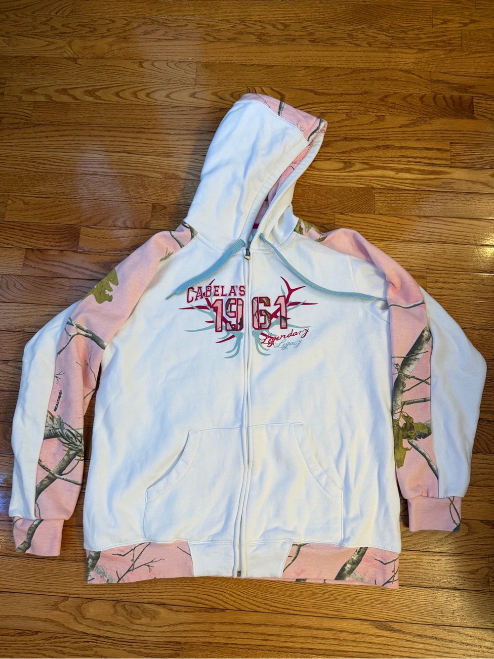 Cabela's White Hoodie with Pink Camo Accents. Front Embroidered Logo. Zip up.